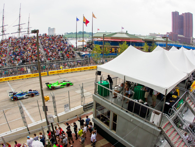 Vantage point view of cars on the track surrounded by crowds.
